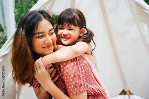 Asian mother and daughter piggy back outdoors at yard.