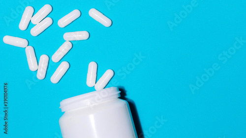 container and white pills on a blue background .
