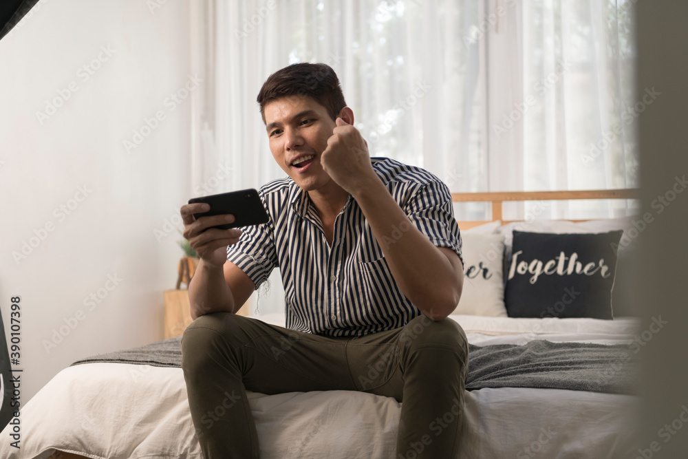 Man playing mobile game on smartphone in bedroom at home.