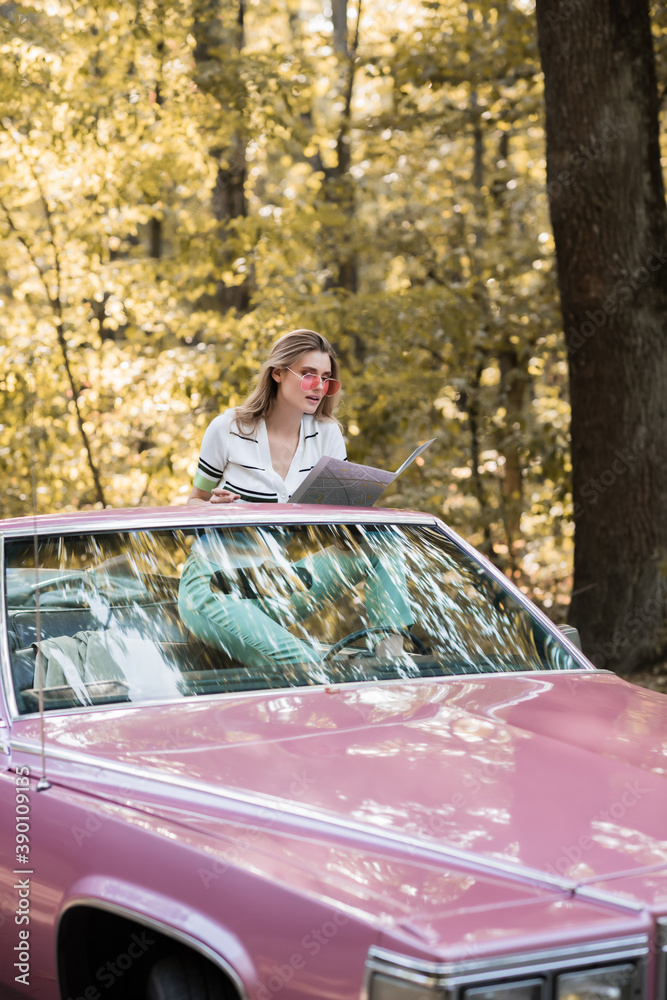 young woman sitting in cabriolet and looking at map in forest young woman sitting in cabriolet and looking at map in forest