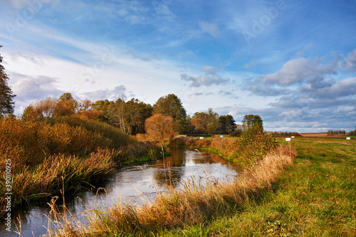 Obraz na płótnie Sunny autumn day on river and meadow. Colorful landscape with forest, field, lake. w salonie