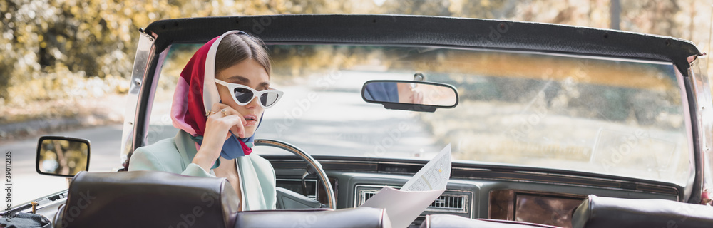 Pensive woman looking at map in retro car on road, banner Pensive woman looking at map in retro car on road, banner