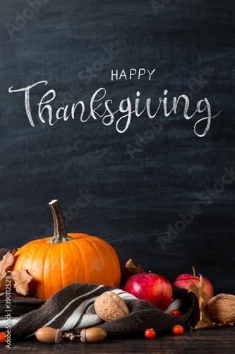 Thanksgiving greetings. Pumpkin, leaves, apples on a chalkboard background, top view. Kaligraphic capital inscription.