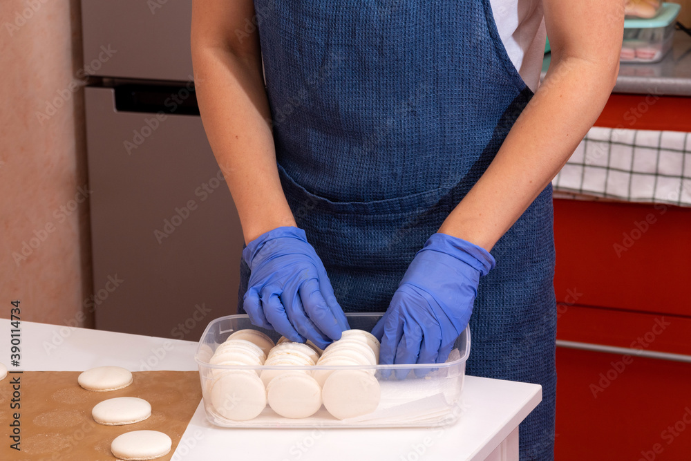 The pastry chef collects macaroons in a container. The pastry chef collects macaroons in a container.