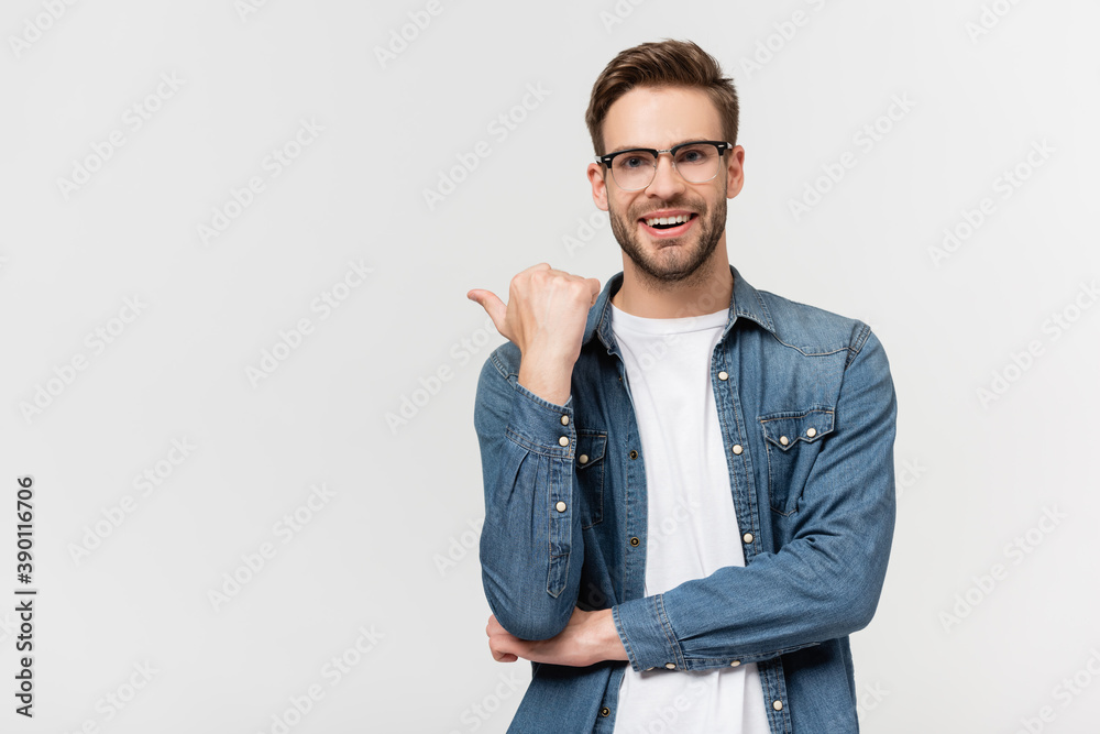 Smiling man in eyeglasses pointing with finger isolated on grey Smiling man in eyeglasses pointing with finger isolated on grey