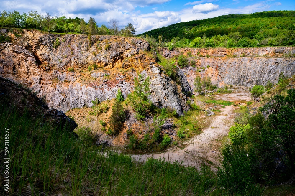 Abandoned quarry with visible layers of sediment in spring day.