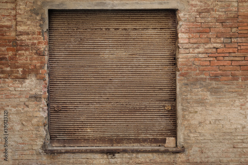 old brick wall with window frame, rusty and dirty rollable jalousie with space for text, 