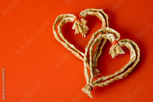 Two hearts made of hay, typical and traditional swedish christmas decoration. Red background with copy space.
