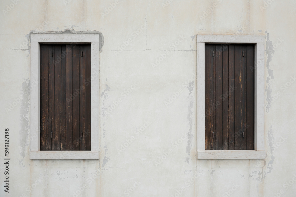 
two old window with wooden shutters on a bright wall, no person an space for text, horizontal 