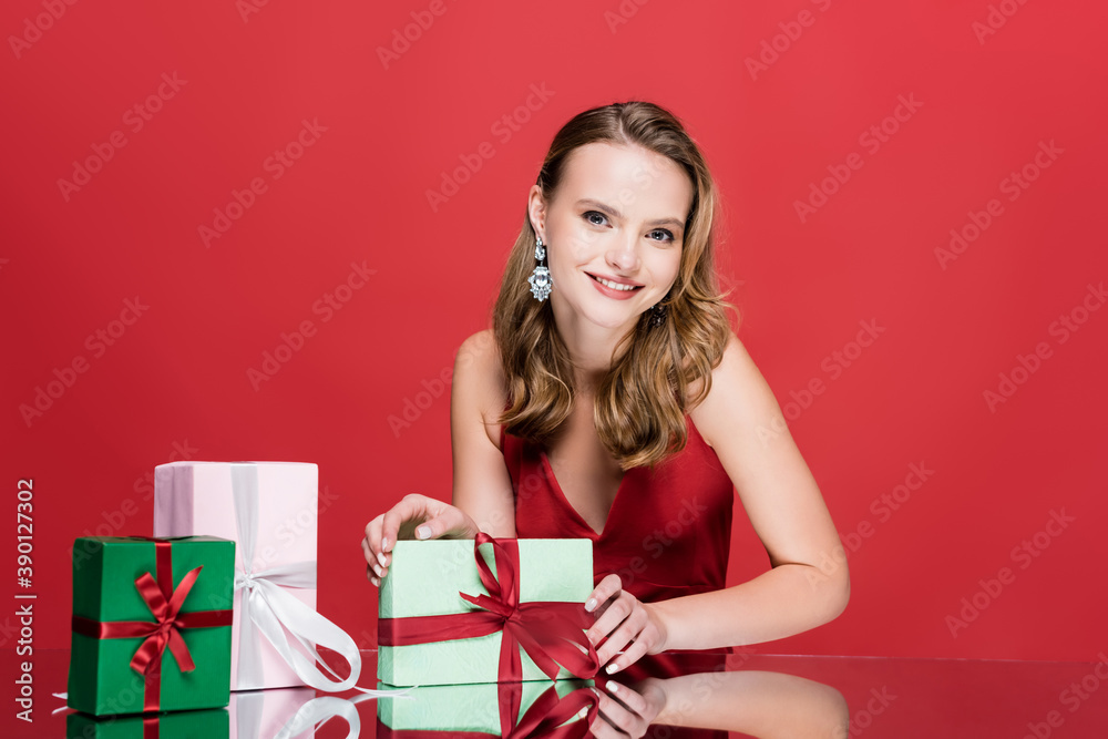 happy young woman smiling near christmas presents on red happy young woman smiling near christmas presents on red