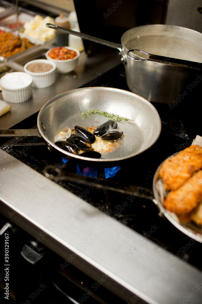 Steamed mussels. Mussels being prepared by a chef in a restaurant kitchen. Classic Italian restaurant entree favorite. Shellfish and seafood prepared with pork, sauces, meats and cheeses. Steamed mussels. Mussels being prepared by a chef in a restaurant kitchen. Classic Italian restaurant entree favorite. Shellfish and seafood prepared with pork, sauces, meats and cheeses.