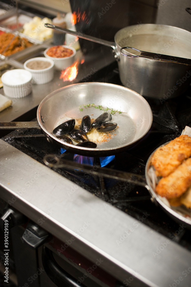 Steamed mussels. Mussels being prepared by a chef in a restaurant kitchen. Classic Italian restaurant entree favorite. Shellfish and seafood prepared with pork, sauces, meats and cheeses. Steamed mussels. Mussels being prepared by a chef in a restaurant kitchen. Classic Italian restaurant entree favorite. Shellfish and seafood prepared with pork, sauces, meats and cheeses.