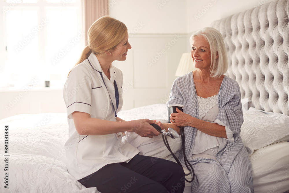 Female Doctor Making Home Visit To Senior Woman In Bedroom For Blood Pressure Check Female Doctor Making Home Visit To Senior Woman In Bedroom For Blood Pressure Check