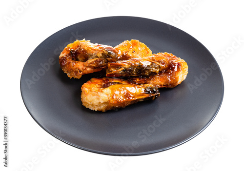 several fried tiger prawns on black plate isolated on white background