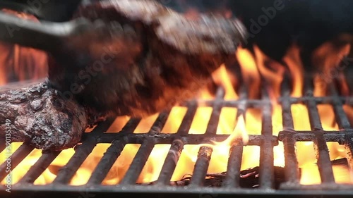 Barbecue grill outside roasting beef meat hot iron grill. chef uses tongs turn meat fillet steaks on grill grate into fire and sparks make delicious street food. barbecue concept street food outside