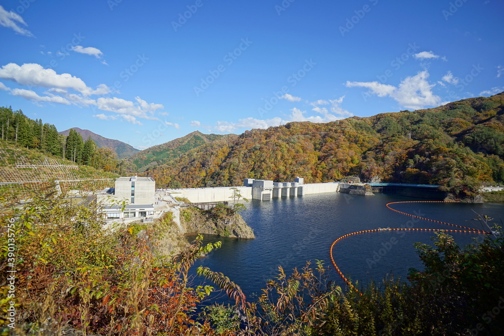 Dam lake on a clear autumn day. The blue sky and the autumnal mountains. Japanese landscape. Beautiful autumn scenery.