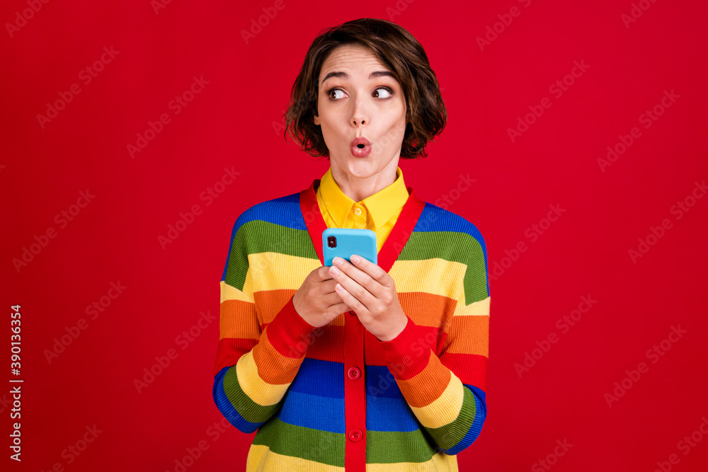 Photo of beautiful amazed lesbian lady blogger hold telephone look side empty space open mouth hear listen interesting secret wear stripes jumper cardigan isolated red color background Photo of beautiful amazed lesbian lady blogger hold telephone look side empty space open mouth hear listen interesting secret wear stripes jumper cardigan isolated red color background