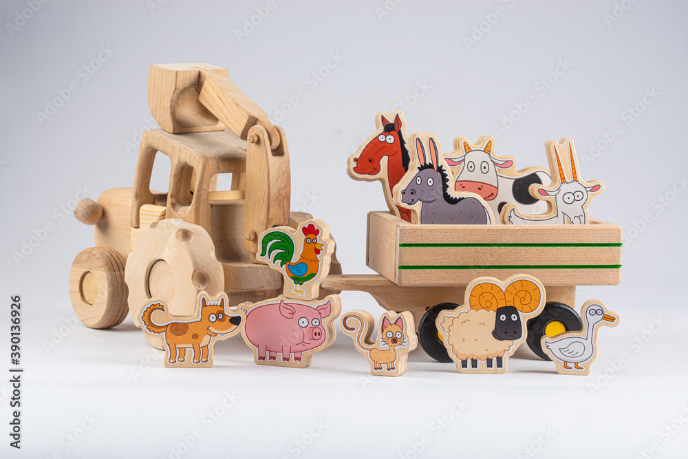Obraz premium wooden kids tractor toy with trailer and cartoon agricultural animals isolated on white background, close view 