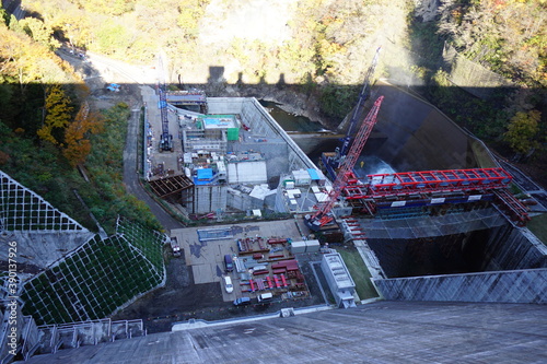 Under construction of a hydroelectric power plant. The blue sky and the autumnal mountains. Japanese landscape. Beautiful autumn scenery.