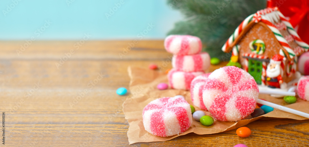 Christmas composition with gingerbread house, peppermint candies and sweets over holiday background. Festive banner with copyspace.