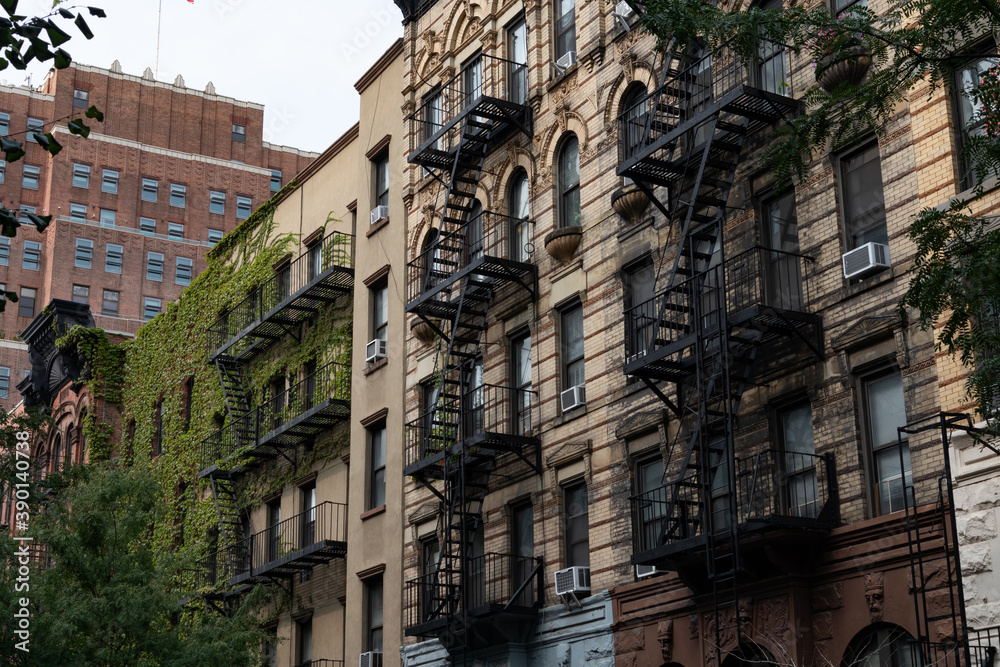 Row of Old Brick Residential Buildings with Fire Escapes and Green Ivy in Chelsea New York