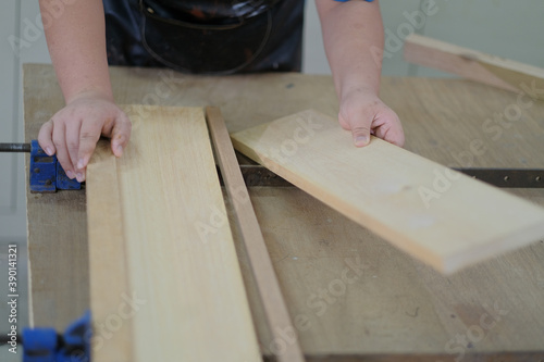 Carpenter joining pieces of wood with long bar clamp and glue.