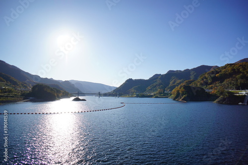 Dam lake on a clear autumn day. The blue sky and the autumnal mountains. Japanese landscape. Beautiful autumn scenery.
