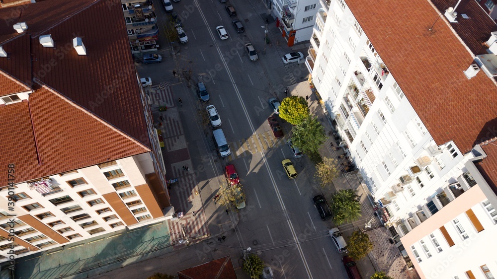Fototapeta premium Aerial view of the city traffics at the center. Vehicles are moving on the road between buildings.