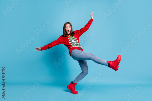 Full length photo of cute charming funky lady stand tiptoe raise hands leg falling open mouth staring afraid funny look wear red sweater jeans boots isolated blue color background