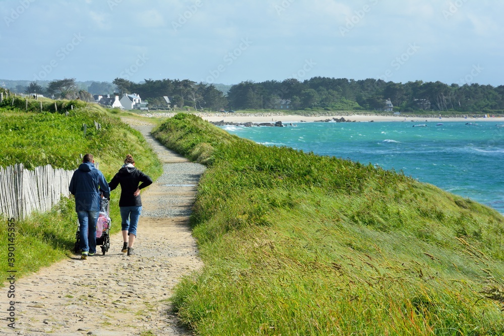 A couple walking along the coast with their baby in a stroller. Brittany, France