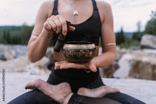 Yogi girl in black suit playing tibetan bowl in marble quarry