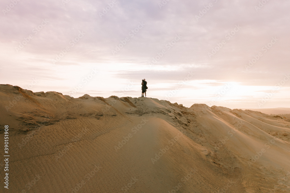 Drone view of a couple in love on the sand dunes at sunset Drone view of a couple in love on the sand dunes at sunset