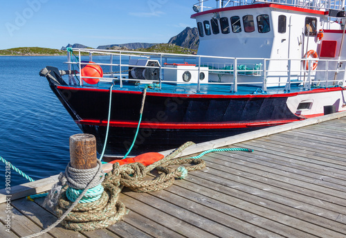 Fishing ship anchored to the mooring in harbor in small town Gjesvaer in the Northern polar Norway photo