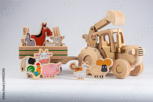 wooden kids tractor toy with trailer and cartoon agricultural animals isolated on white background, close view 