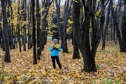 woman in blue jacket in autumn park with yellow foliage