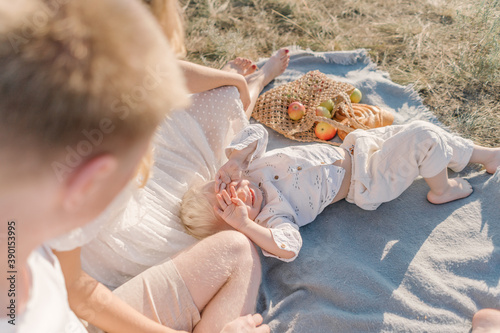 Parents look at a child lying next to a bag of fruits at sunset
