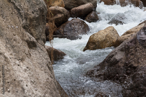 Close up of a little cascade falls of water over mountain river rocks. © Jirattawut