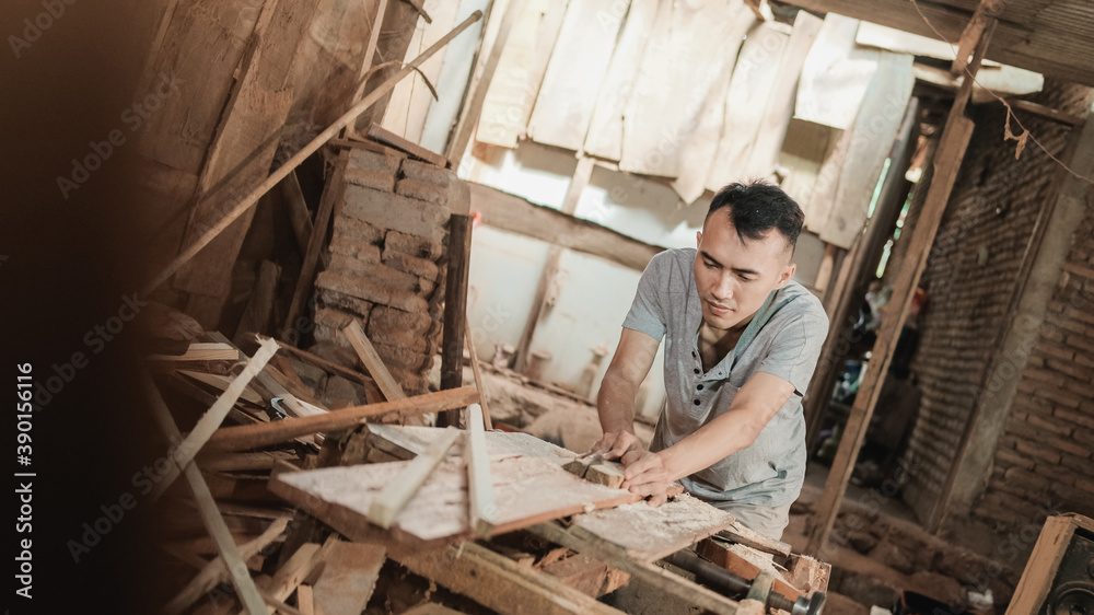 Asian carpenters cut wood planks using a circular saw in a traditional workshop