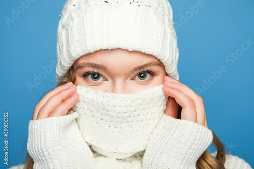 beautiful woman covering mouth with scarf on blue background