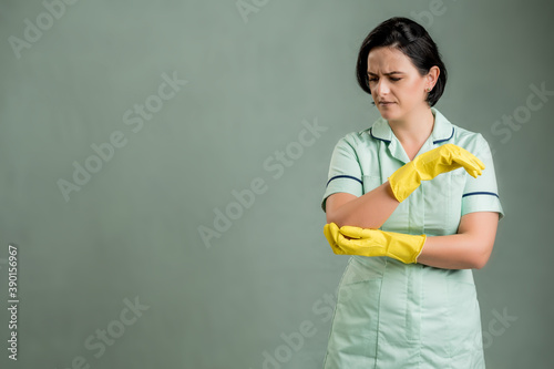 Young cleaning woman wearing a green shirt and yellow gloves has elbow pain © Cipri Suciu 