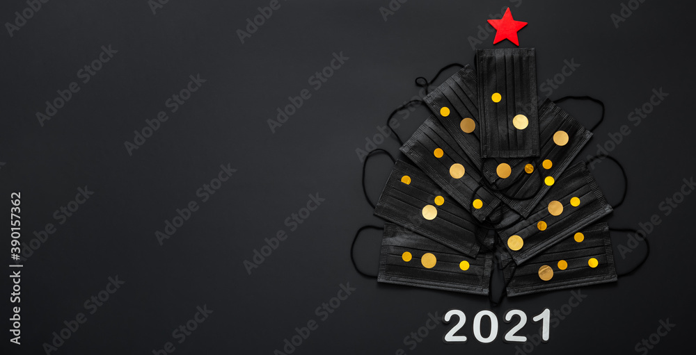 Christmas tree made from face masks and gold festive decor confetti. Face masks on black background. 2021 invitation card for New Year Eve with Copy space. Covid 19 hygiene long web banner - obrazy, fototapety, plakaty 