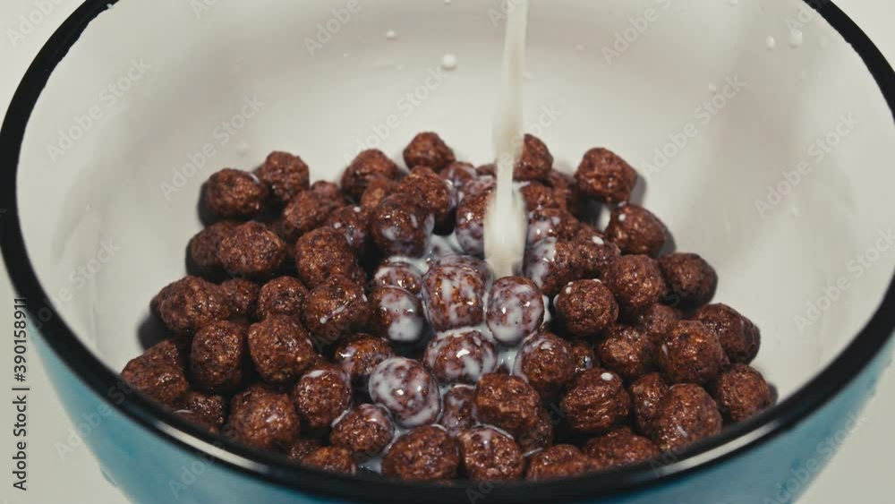 close up. milk is poured into breakfast cereals chocolate corn balls close up. milk is poured into breakfast cereals chocolate corn balls