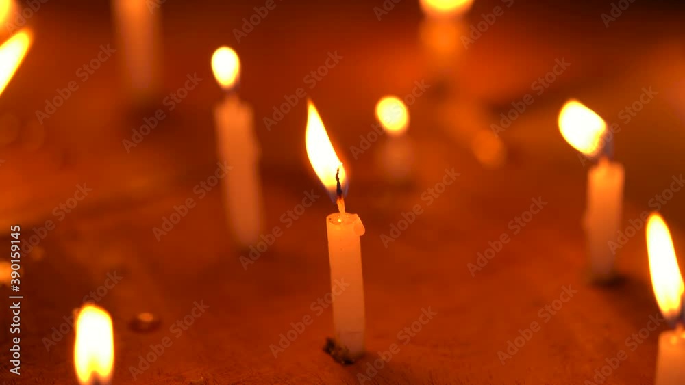 Candles are burning with big yellow flames at a temple or church on a windy night. Concept for Diwali, Christmas, festive celebration, pray, hope, belief, protest, grief.