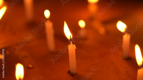 Candles are burning with big yellow flames at a temple or church on a windy night. Concept for Diwali, Christmas, festive celebration, pray, hope, belief, protest, grief.