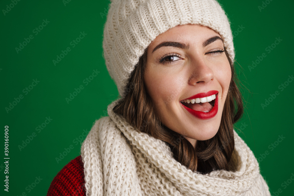 Beautiful happy girl in knit hat and scarf winking at camera Beautiful happy girl in knit hat and scarf winking at camera