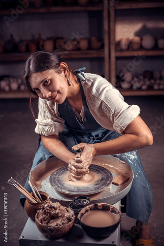 Stylish potter master woman posing while making earthenware. Manual work.