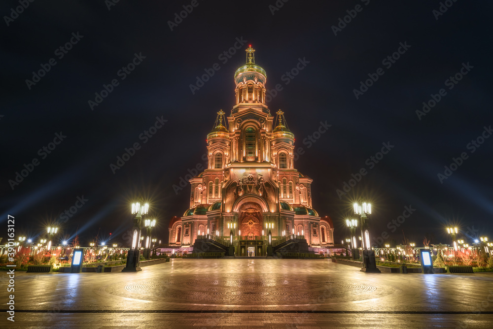 Front view from of the Main Cathedral of the Russian Armed Forces in honor of the Resurrection of Christ with bell tower at Patriot theme park in Kubinka illuminated in gold color in the dusk..