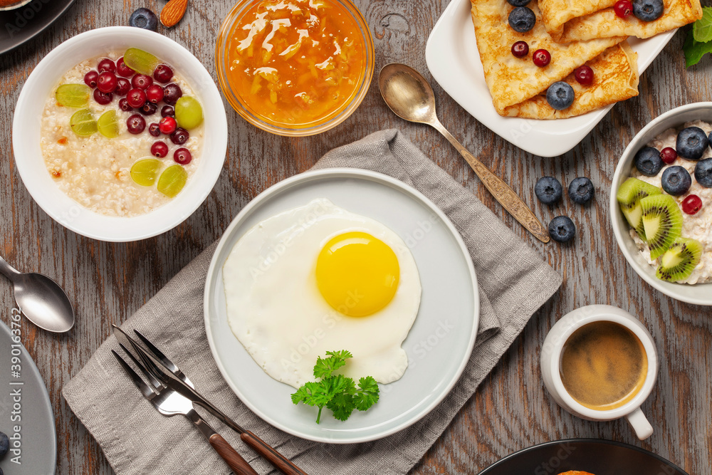 Continental breakfast captured from above (top view, flat lay). Coffee, tea, croissants, jam, egg, pancakes, maffins and oatmeal. Wooden background. Family breakfast table. Continental breakfast captured from above (top view, flat lay). Coffee, tea, croissants, jam, egg, pancakes, maffins and oatmeal. Wooden background. Family breakfast table.