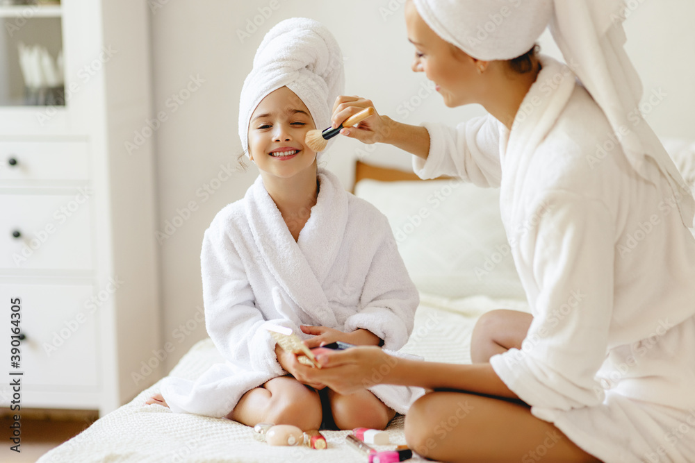 happy family mother and little daughter in dressing gowns and towels laugh and do makeup Spa day at home . happy family mother and little daughter in dressing gowns and towels laugh and do makeup Spa day at home .