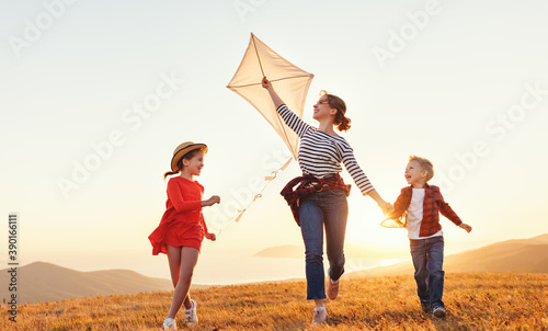 Happy family  mother and kids  launch  kite on nature at sunset. photo